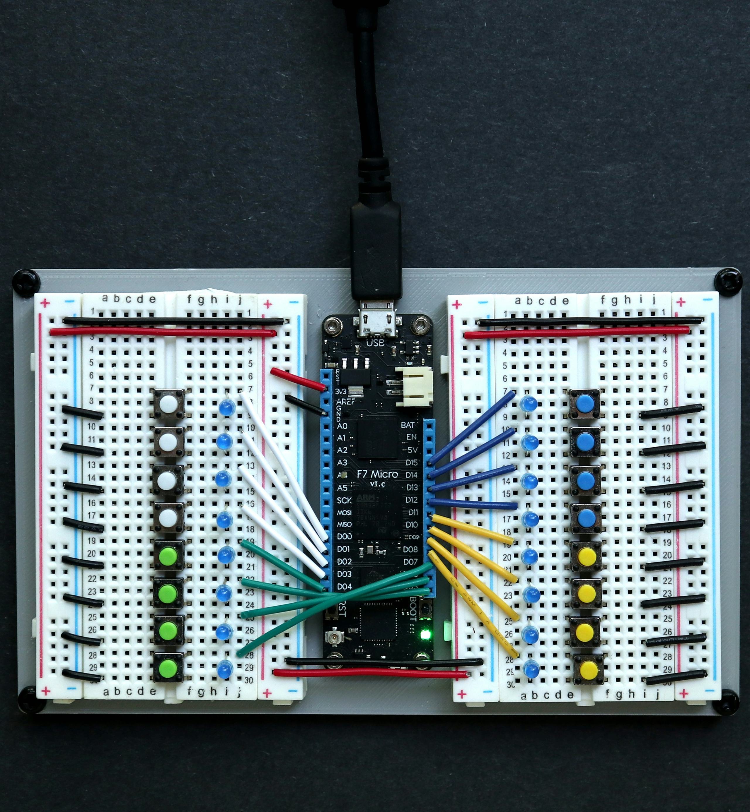 Prototyping breadboards with a microcontroller board, LEDs and jumper wires, seen from above
