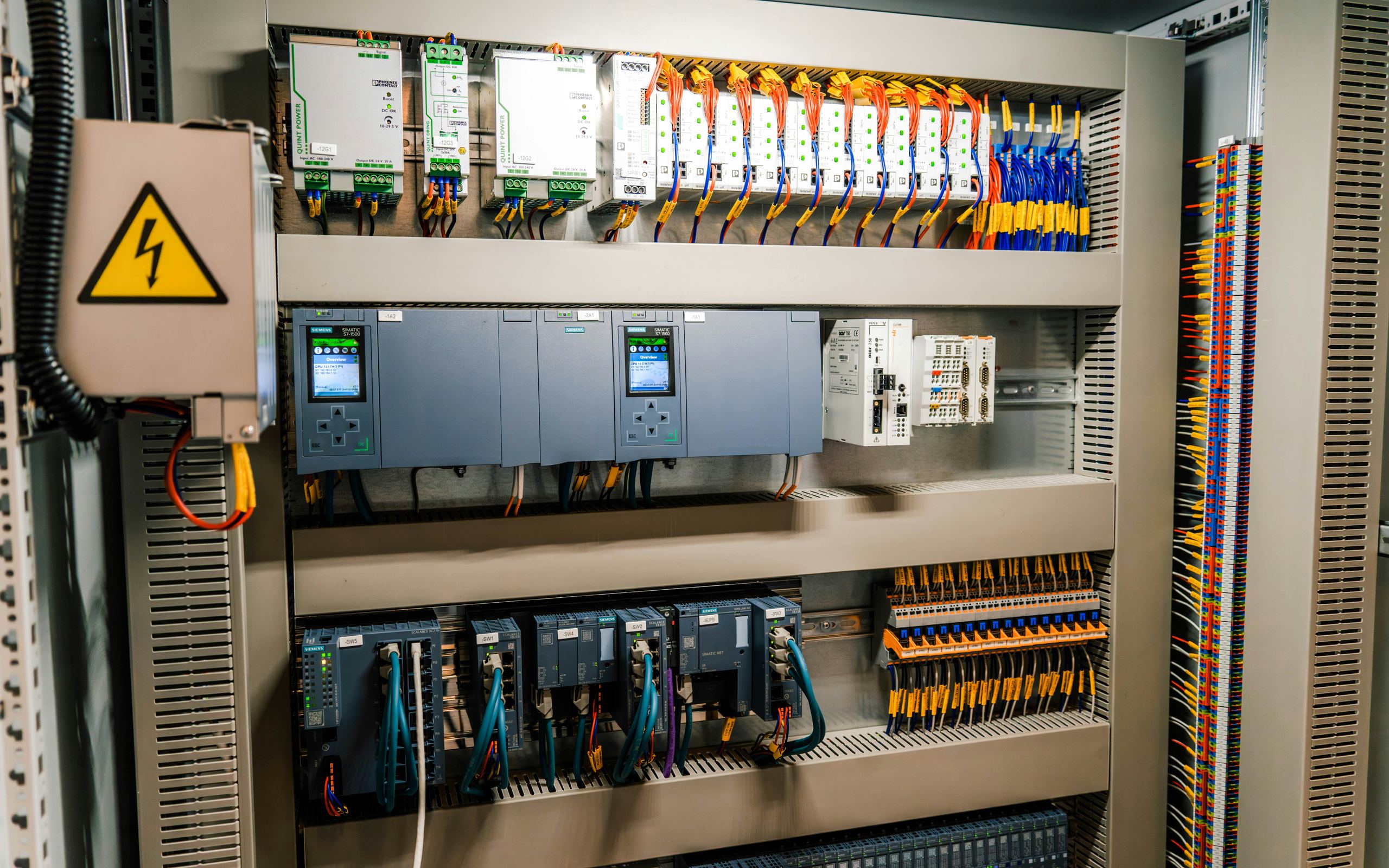 Control cabinet interior with PLCs on DIN rail, terminal blocks and field wiring