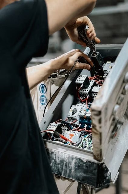 Hands wiring contactors and circuit breakers inside a control panel