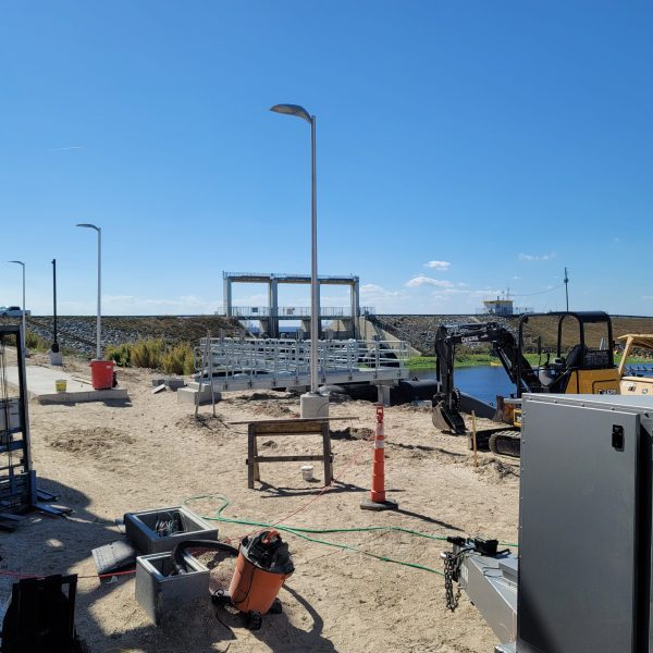 Controls cabinet being installed beside weir gates at a water treatment structure under construction
