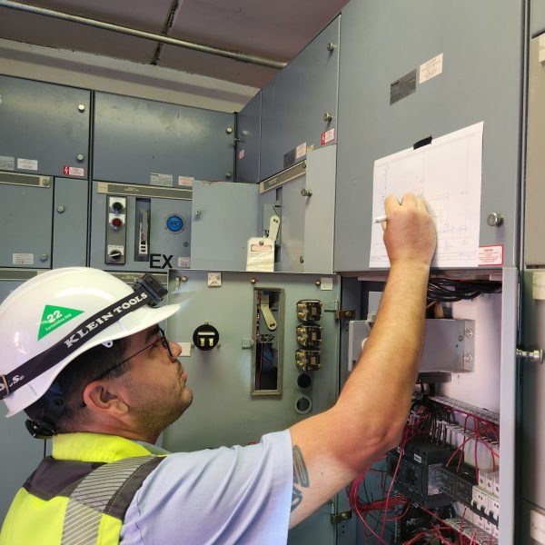 Technician working inside a live control panel