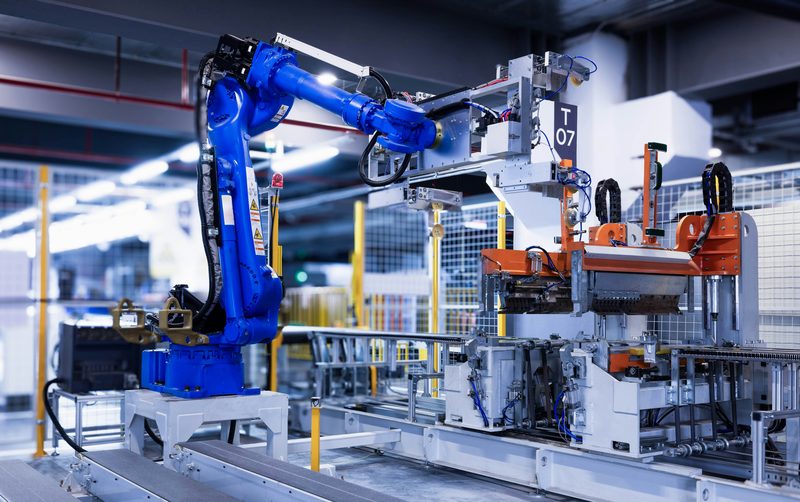 Six-axis robot arm serving an automated assembly line inside a production hall
