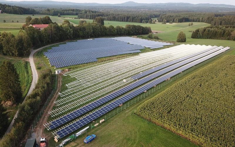 Aerial view of a ground-mounted solar farm beside farmland
