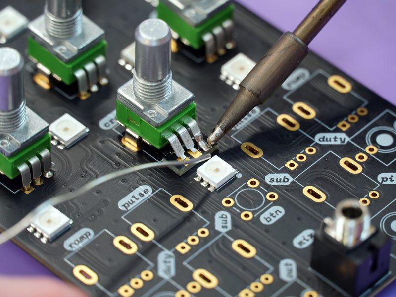 Soldering iron working on a control board with switches and indicator LEDs